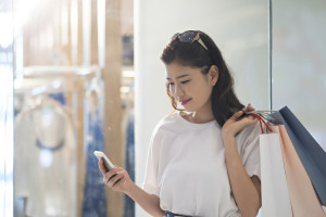 Woman Looking at Phone While Shopping